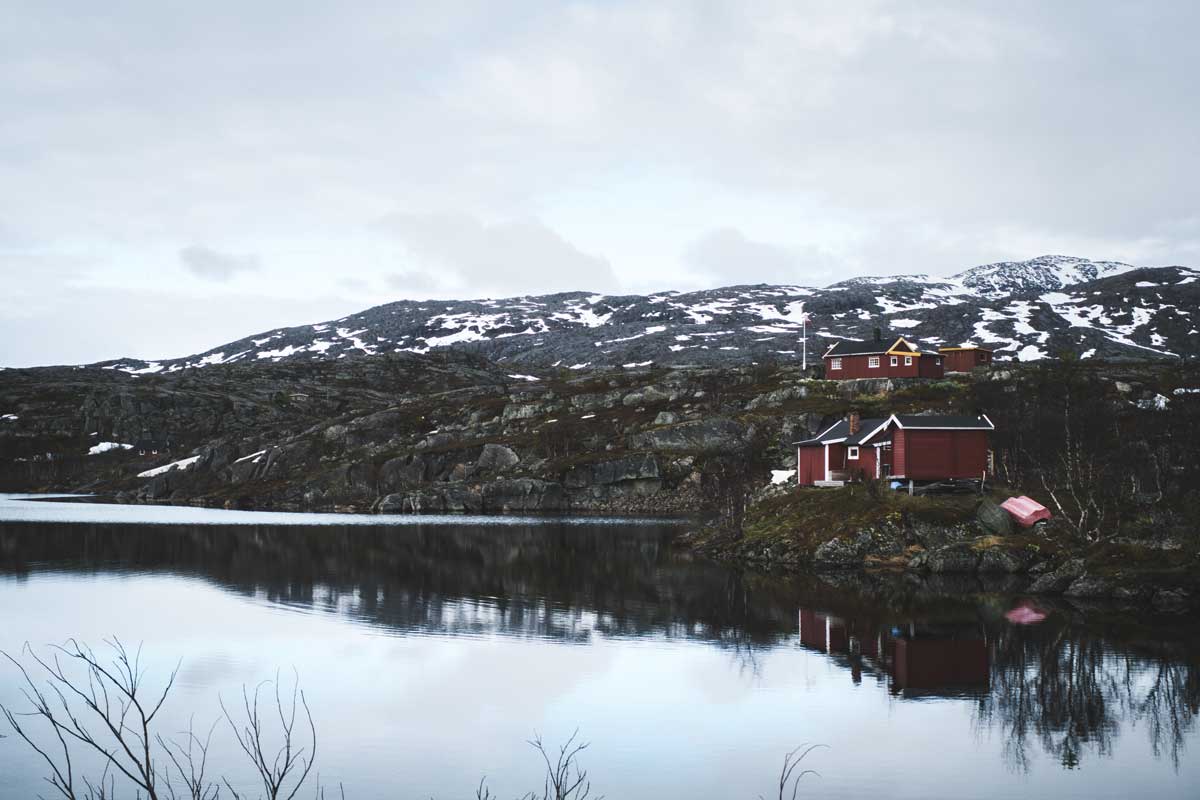 Rote Holzhäuser an einem See an der Grenze von Schweden und Norwegen