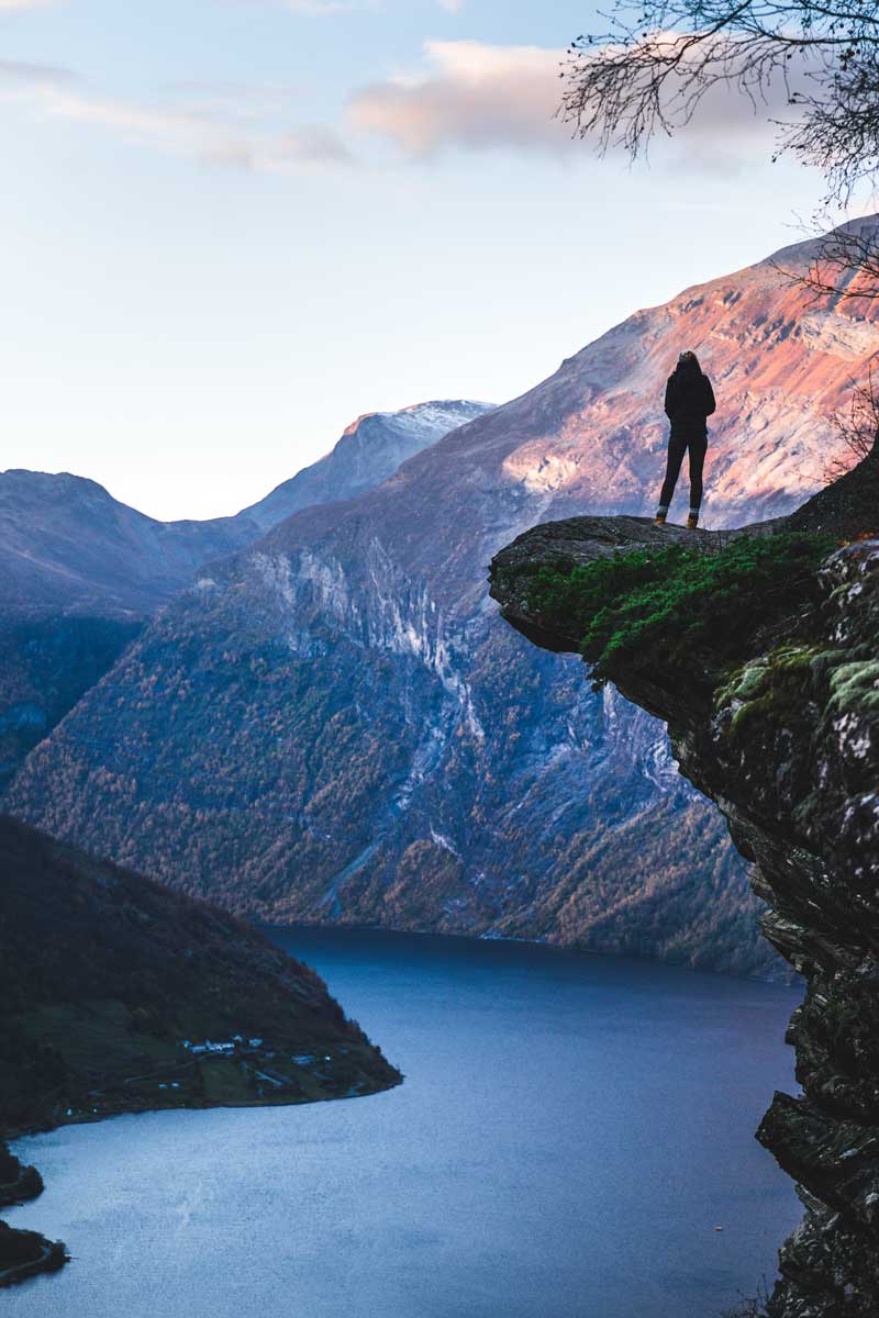 Frau posiert an einer Klippe am Geirangerfjord